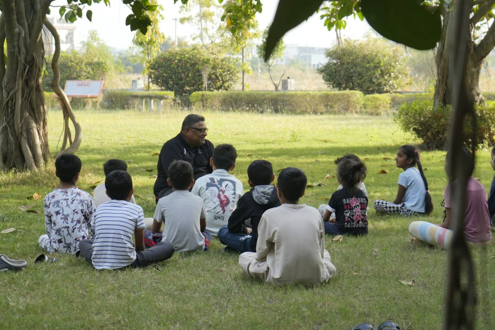 Un adulto comparte una historia con un grupo de niños al aire libre.